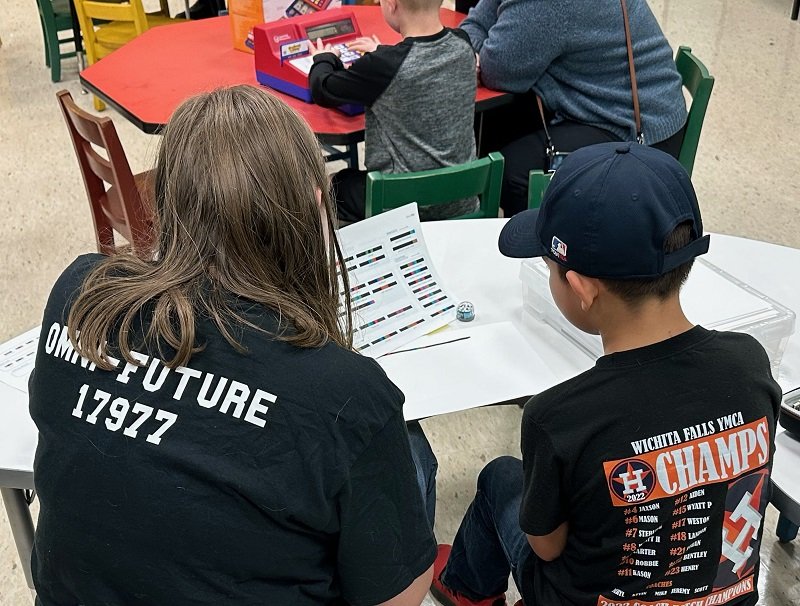 A patron and an Omni Future Robotics team member learning about a robot