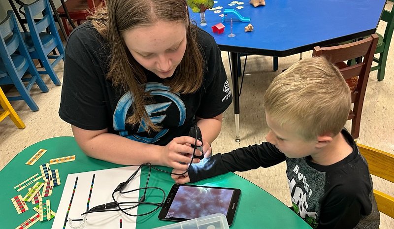 A patron and an Omni Future Robotics team member using a digital microscope