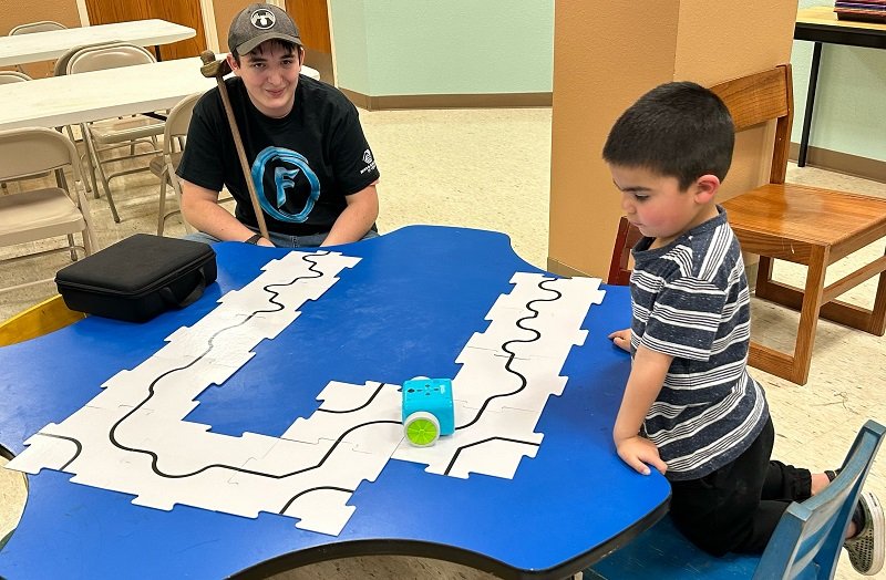 A patron and an Omni Future Robotics team member learning about a robot