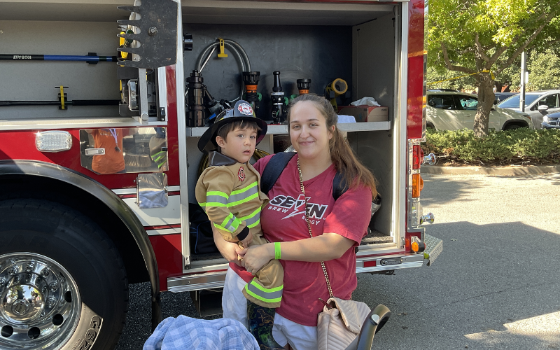 A young patron dressed as a fire fighter getting to see a fire engine up close