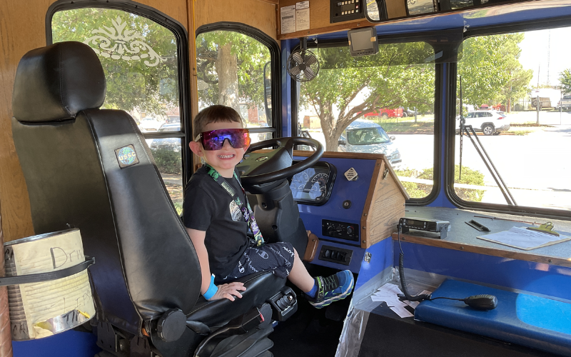 A young patron sits in the driver's set of the Falls Town Trolley