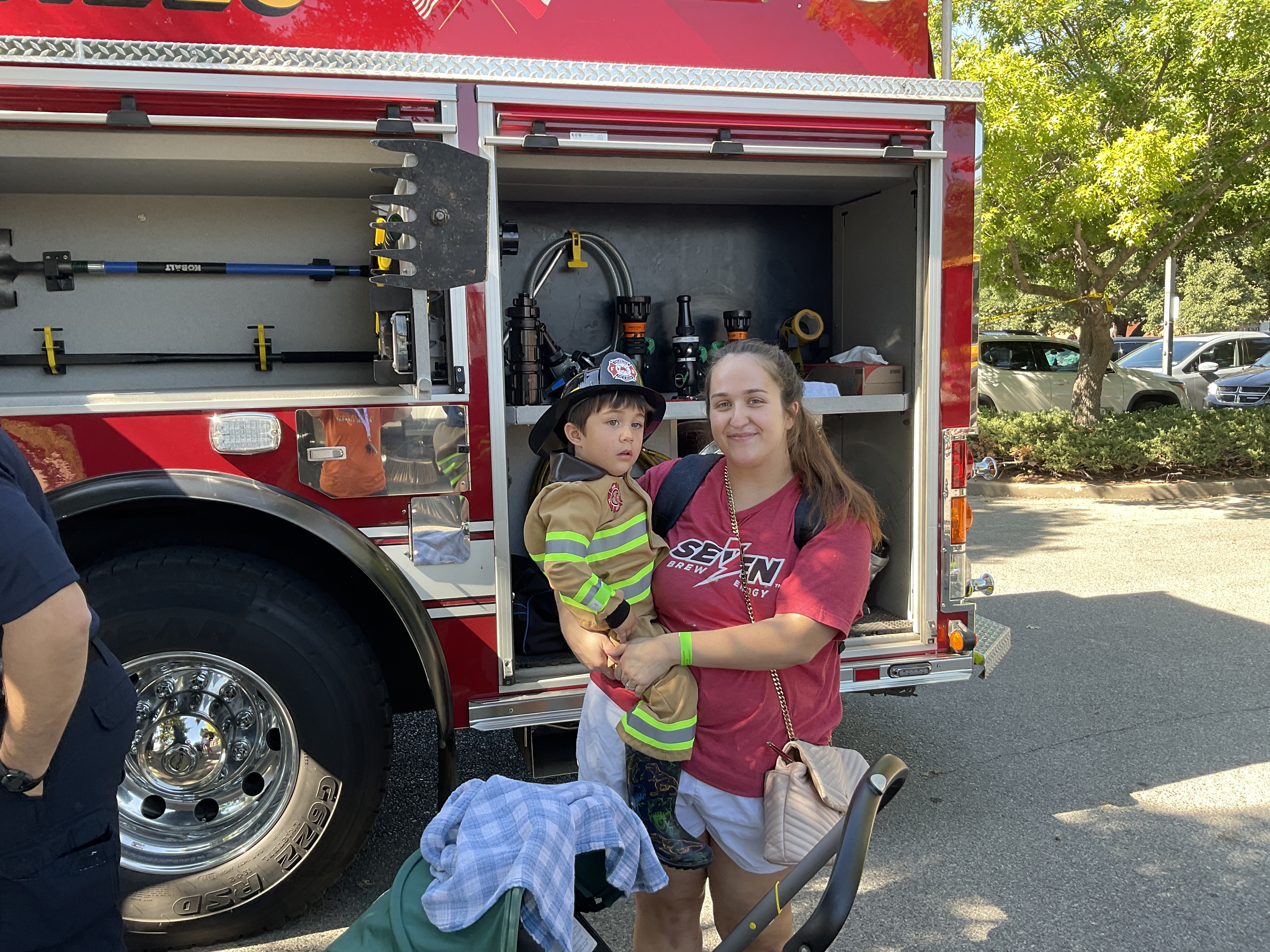 A child dressed as a fire fighter next to a fire truck
